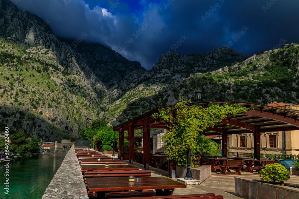 Outdoor restaurant with a view of Kotor Bay and hillside of Saint John Mountain outside Old Town of Kotor, Montenegro