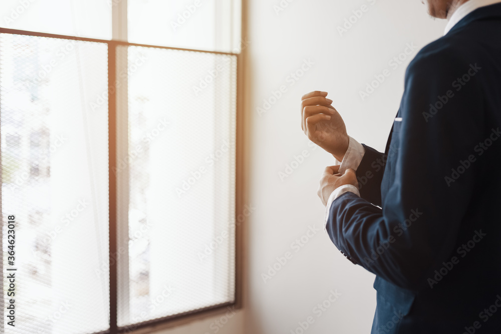 businessman wearing business suit fasten cufflink or button on sleeve of classic jacket and factory background. businessman wearing business suit fasten cufflink or button on sleeve of classic jacket and factory background.