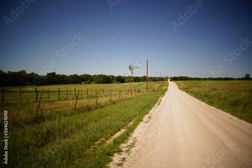 A farm windmill in the Kansas countryside along a dirt road.