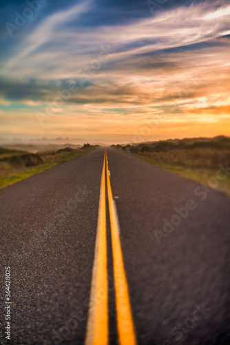 Highway with yellow lines and sunset sky, selective focus. Dreamy pic