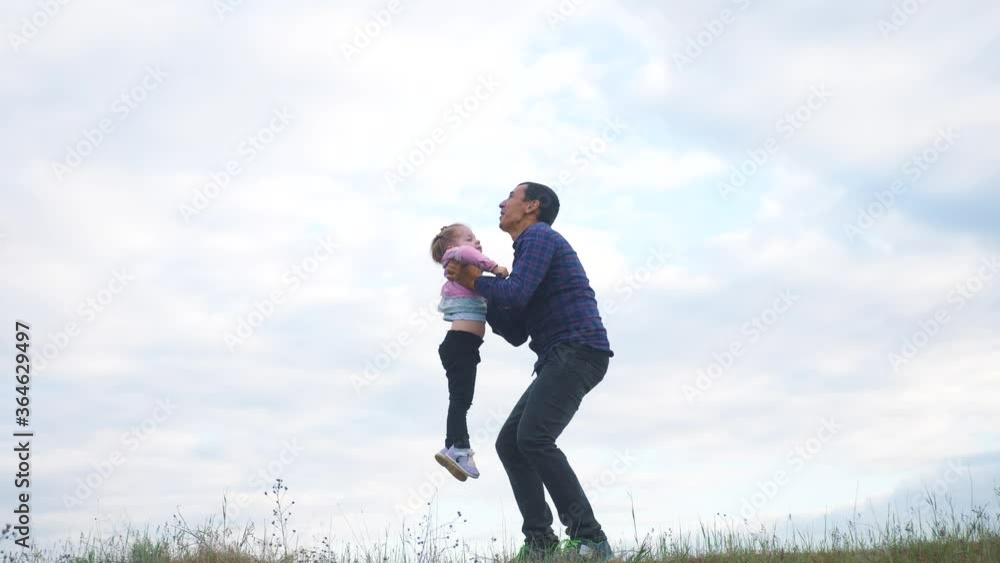 happy family. Dad throws daughter in his arms up in nature. man father plays with little girl lifestyle daughter throws up in the sky