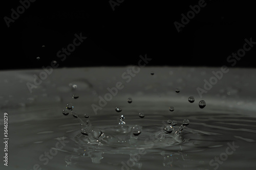 splash de gotas de agua sobre base blanca y fondo negro