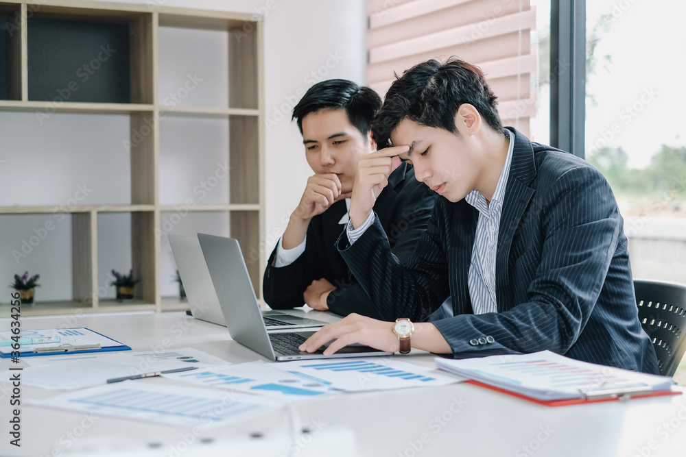 Stressed young asian business man working on laptop computer at office. Stressed young asian business man working on laptop computer at office.
