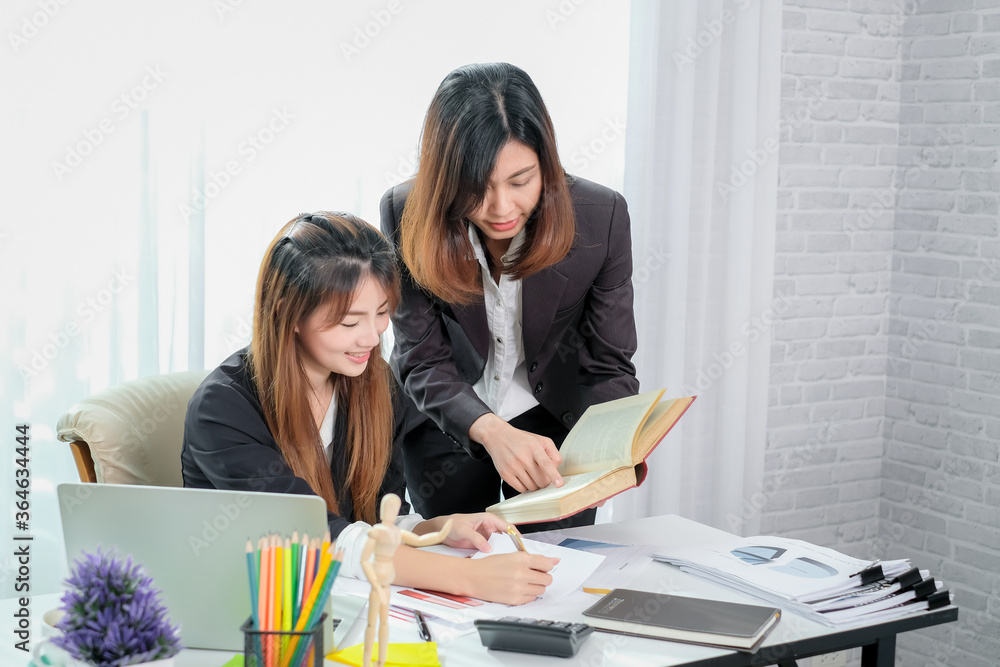 Two business women working together with a laptop computer to explain and discuss on business in the office. Two business women working together with a laptop computer to explain and discuss on business in the office.