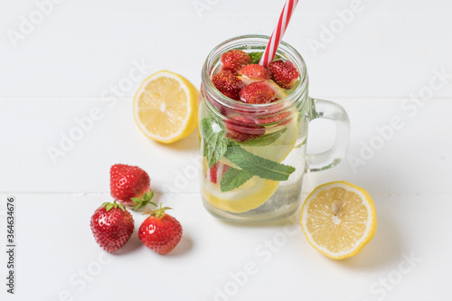 A mug with a red tube and a cold drink made of lemon and berries.