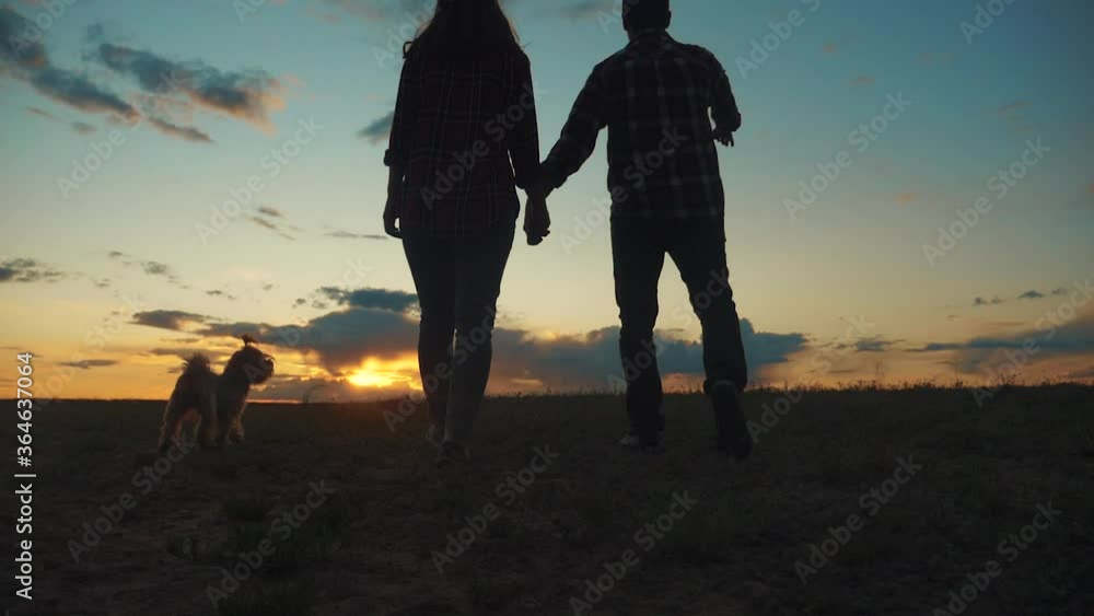 happy family couple and dog runs hands at lifestyle sunset on a hilltop ...