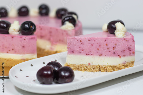 Cherry cheesecake on white plate sliced cake.