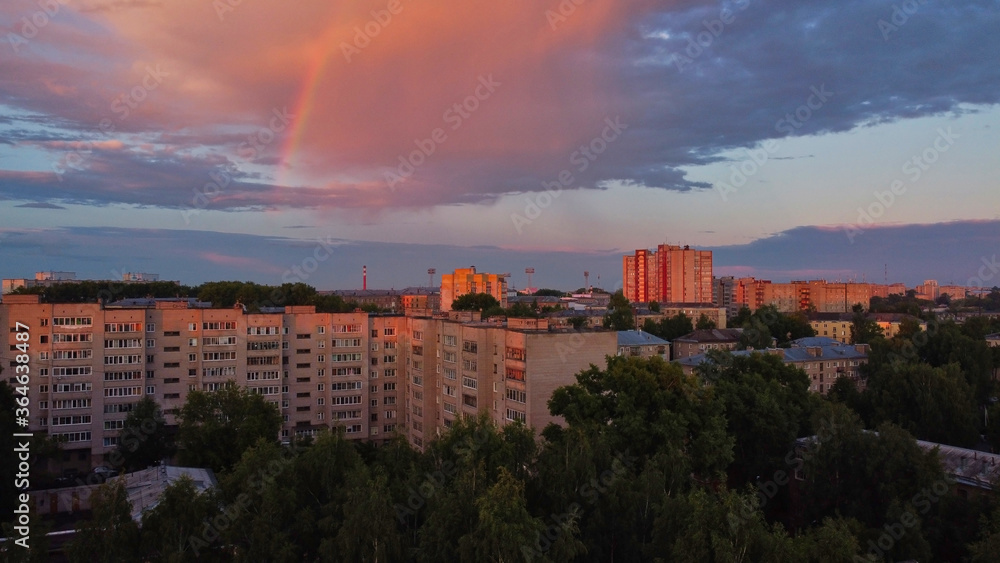 Rainbow over city in summer evening