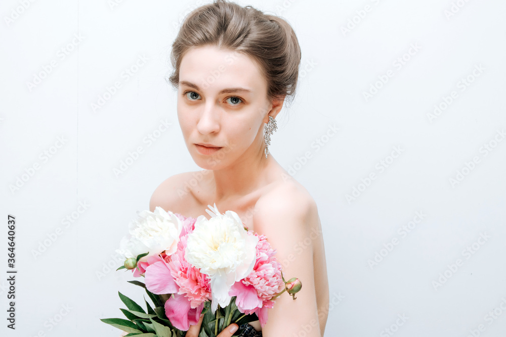 Sexy lady with a bouquet of peonie. Young woman with bare shoulders. Sensual portrait