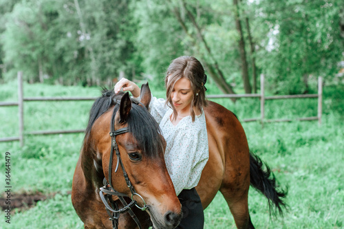 Young woman with horse in forest. Brunette girl and brown horse