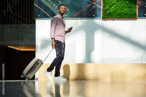 African young businessman walking along the corridor with luggage at the airport he has a business trip