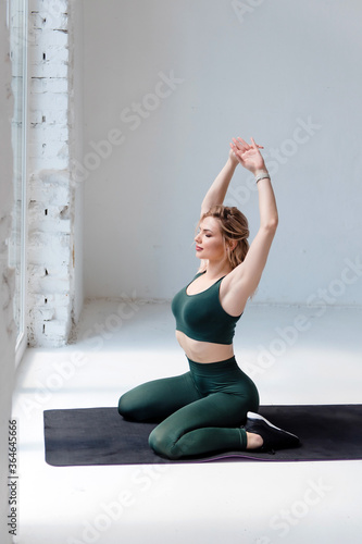 Beautiful healthy girl stretching body on yoga mat