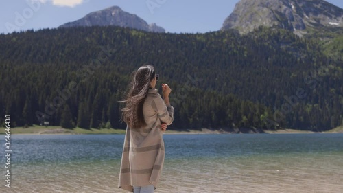 attractive woman relax in mountains with lake view on vacations. Authentic woman traveller standing near lake and forest view in summer day. 