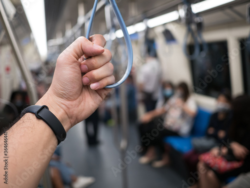 Hand of man holding the handle on the subway or sky train, traveling in the city