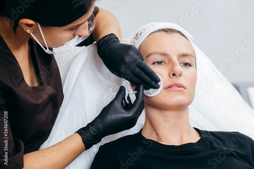 Doctor in gloves  giving woman injections in lips photo