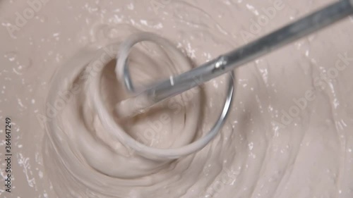 Slow motion pan shot of mixing concrete plaster with electric mixer. spatula and bucket with mortar on the construction site.

