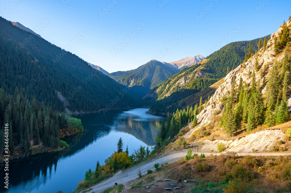 Kolsay (Kolsai) National Park, Lower Lake, Kazakhstan adventure travel, scenic landscape, view over turquoise color lake (tarn), mountains wood with huge Tian Shan pine trees, blue sky on a sunny day