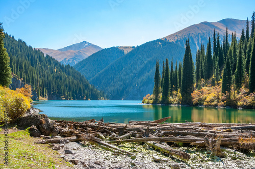 Kolsay (Kolsai) National Park, Middle Lake, Kazakhstan adventure travel, scenic landscape, view over turquoise color lake (tarn), mountains wood with huge Tian Shan pine trees, blue sky on a sunny day