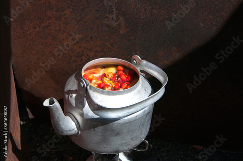 Kompot, a fruit drink made of apples, pears and rose hips boiling in a kettle at the picnic photo