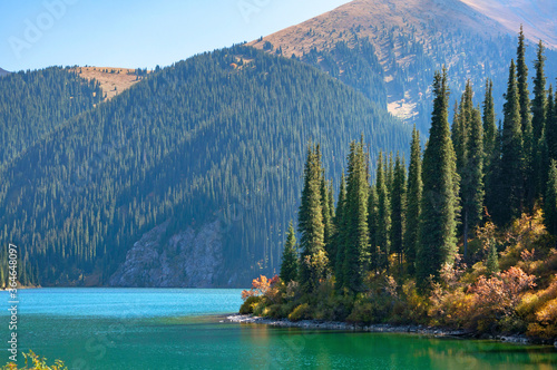 Kolsay (Kolsai) National Park, Middle Lake, Kazakhstan adventure travel, scenic landscape, view over turquoise color lake (tarn), mountains wood with huge Tian Shan pine trees, blue sky on a sunny day photo