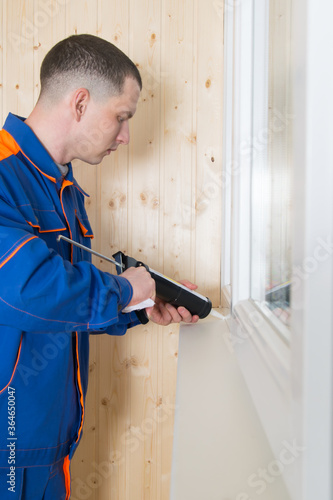 close-up, window installation wizard, smears the cracks with silicone, a special gun