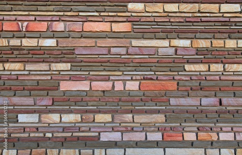 Surface and texture of multy-colored (colorful) decorative stone wall, background. Varicolored flat stones of regular shape in the wall construction. Stylish decorative stone laying. Modern design