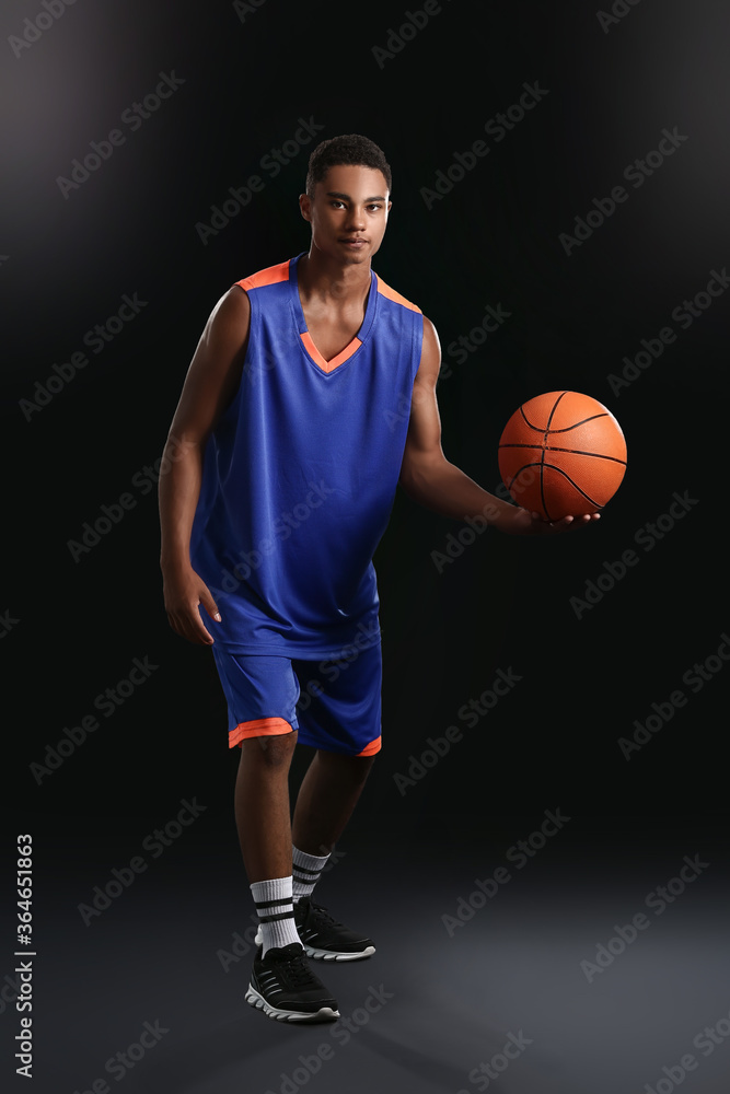 Young African-American basketball player on dark background Young African-American basketball player on dark background