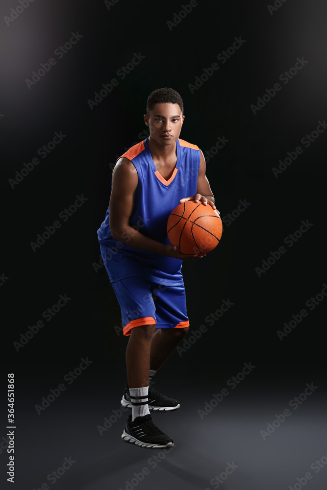 Young African-American basketball player on dark background Young African-American basketball player on dark background