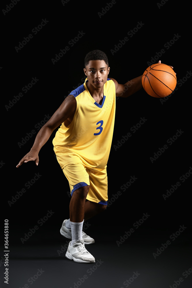 Young African-American basketball player on dark background Young African-American basketball player on dark background