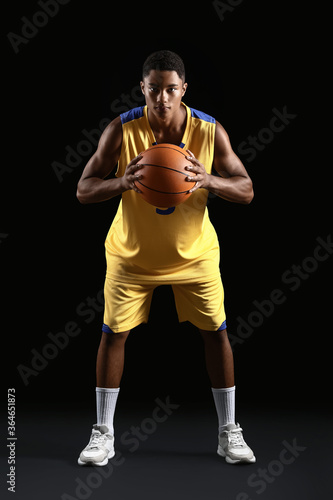 Young African-American basketball player on dark background © Pixel-Shot