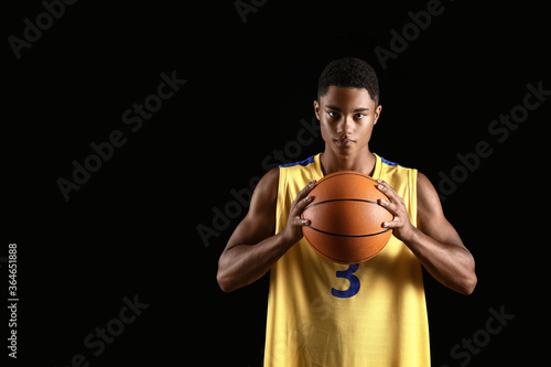 Young African-American basketball player on dark background © Pixel-Shot
