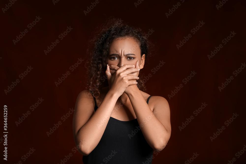 Scared African-American woman on dark background. Stop racism