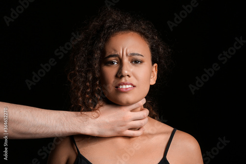 Man strangling African-American woman on dark background. Stop racism photo