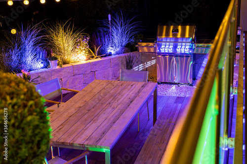 Gas barbecue on a stylish illuminated wooden terrace