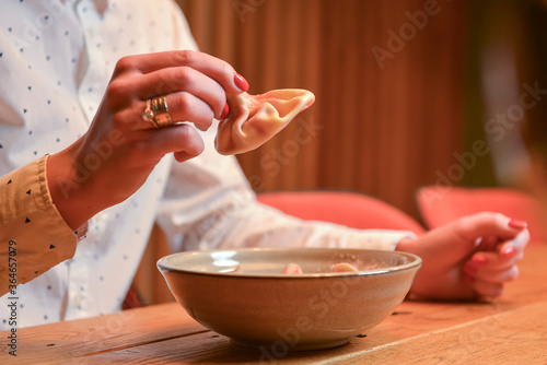 Young woman eats khinkali with meat in a restaurant. National Georgian cuisine. How to eat khinkali. Lifestyle.