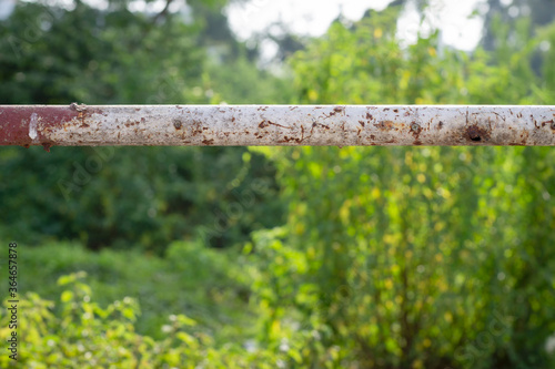 close up of old rusty steel post on blur plant background