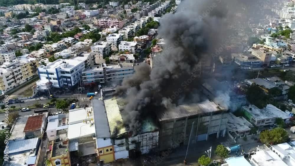 Aerial, tilt, drone shot a building on fire, due to a explosion, dark smoke rising, in Santo Domingo city, Dominican Republic