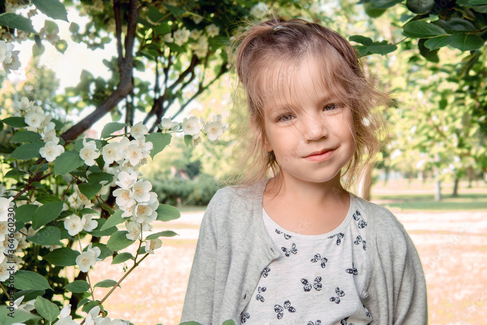 Portrait of beautiful little girl 4-7 years old with blue-green emerald eyes in flowering spring summer park on natural background Portrait of beautiful little girl 4-7 years old with blue-green emerald eyes in flowering spring summer park on natural background