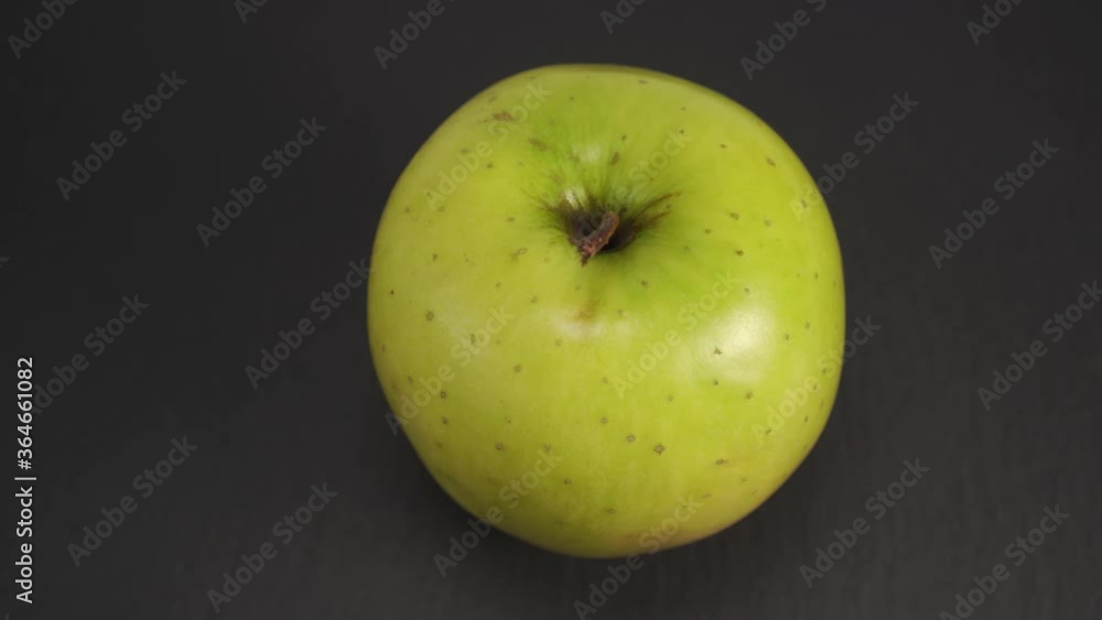 Ripe green apple on a dark background close-up. Stone texture surface. Slow rotation. Nutritious ingredients Ripe green apple on a dark background close-up. Stone texture surface. Slow rotation. Nutritious ingredients