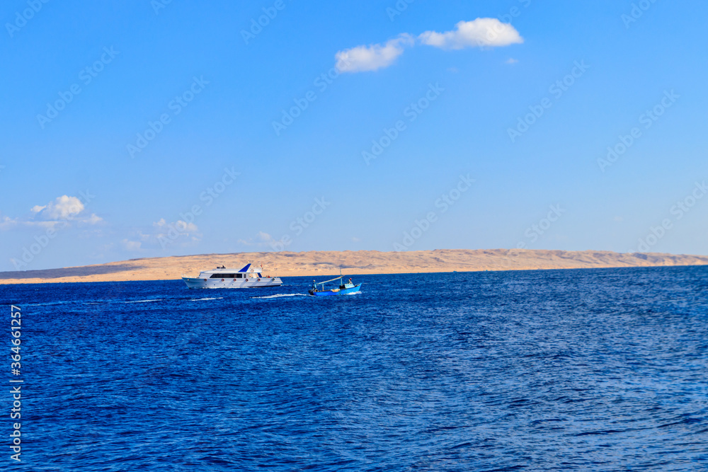 Old fishing boat and white luxury yacht sails in the Red sea, Egypt