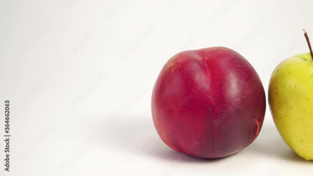 Hand picks up a ripe apple from a white table with red nectarine. Diet Food and Cocktail Ingredients Concept Hand picks up a ripe apple from a white table with red nectarine. Diet Food and Cocktail Ingredients Concept