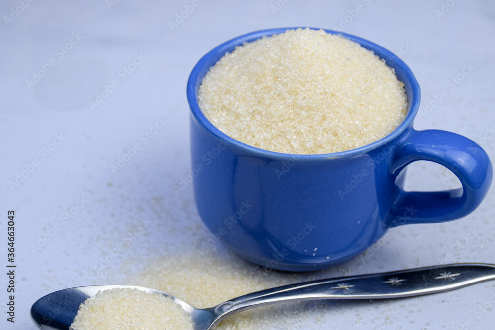 White Sugar in a cup with spoon, diabetes concept White Sugar in a cup with spoon, diabetes concept