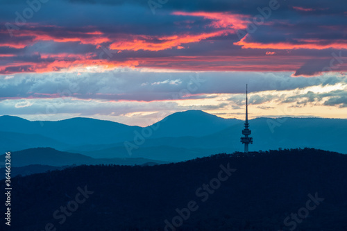 Canberra tower with colourful sunset and layers of clouds and mountains in the background