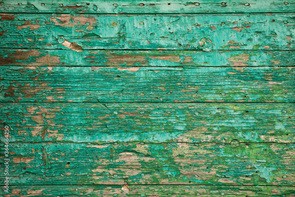 Old wooden board with peeling paint. Background of green flaky paint on cracked plank of wood