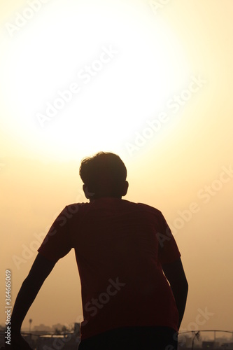   young bettry boy  hiking on top of building in dark shadow over looking san diego at sunset © Kishan