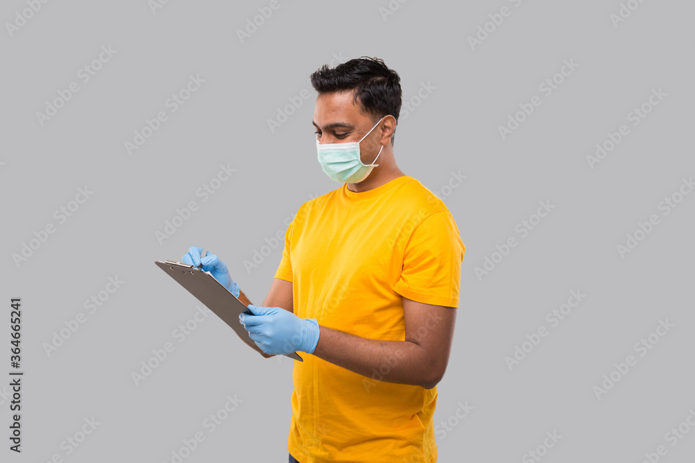 Indian Man Writing in clipboard Wearing Medical Mask and Gloves. Indian man Clipboard Indian Man Writing in clipboard Wearing Medical Mask and Gloves. Indian man Clipboard