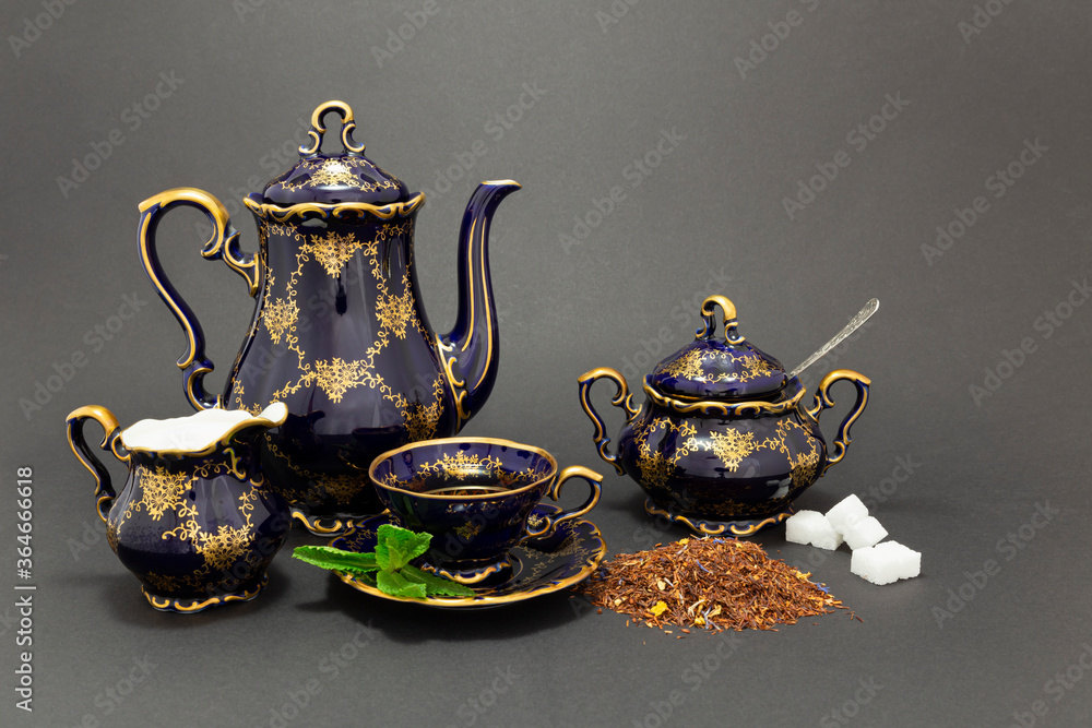 Φωτογραφία Still life with a cobalt blue vintage porcelain tea set, spoon with sugar cubes, sugar bowl, milk jug and dry tea leaves