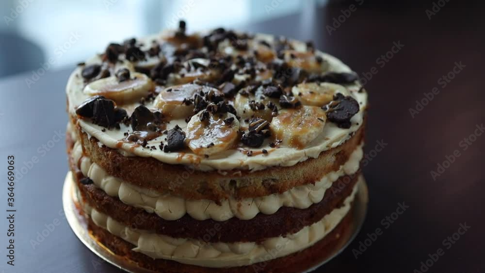 sponge naked cake covered with cream with bananas and sprinkled with chocolate on the table sponge naked cake covered with cream with bananas and sprinkled with chocolate on the table