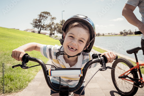 Portrait of cheerful cute kid with helmet riding his bike at the park