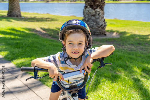 Portrait of cheerful cute kid with helmet riding his bike at the park